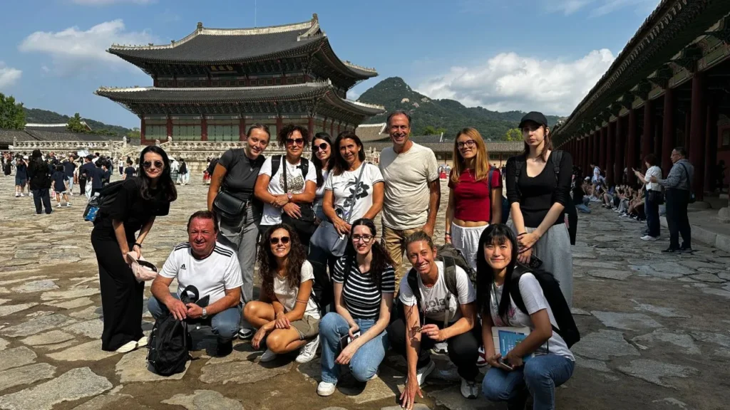 Gruppo di viaggiatori di Explora nel Mondo in posa davanti al padiglione principale del Palazzo Gyeongbokgung a Seoul, Corea del Sud.