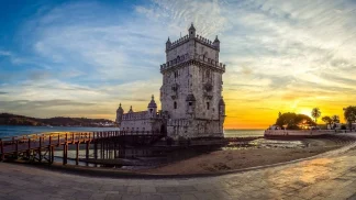 Veduta della Torre di Belém al tramonto con passerella in legno, simbolo di Lisbona durante un viaggio organizzato in Portogallo.
